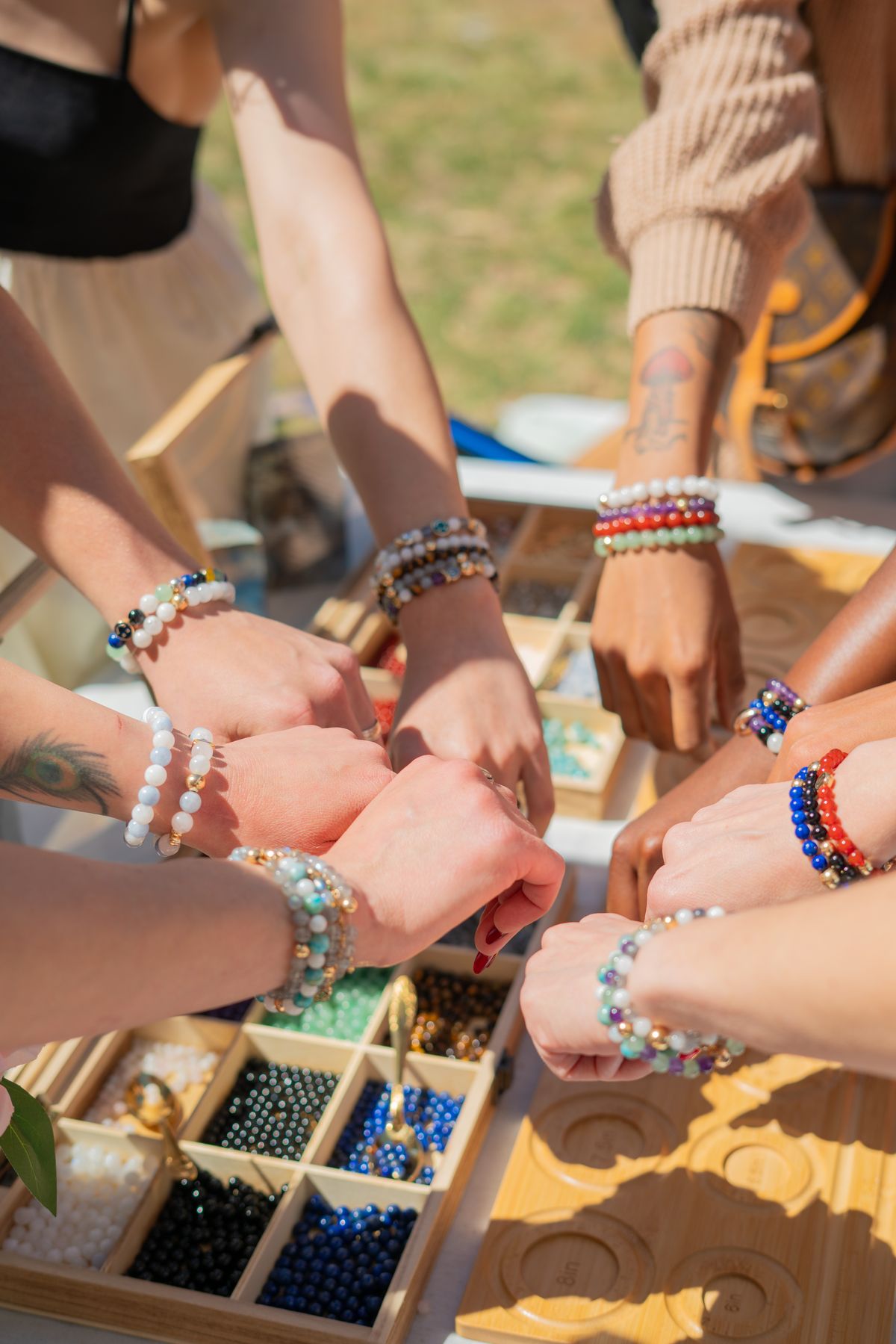 Guests stacking their finished crystal bracelets over the bead tray at The Stack Sessions