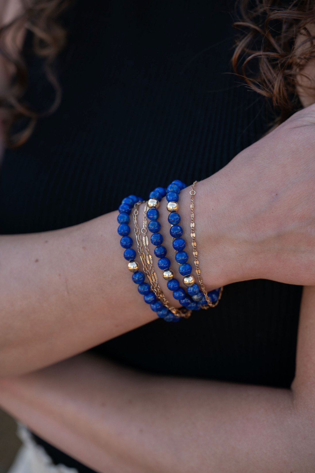 Lapis lazuli and gold bracelets stacked on a wrist