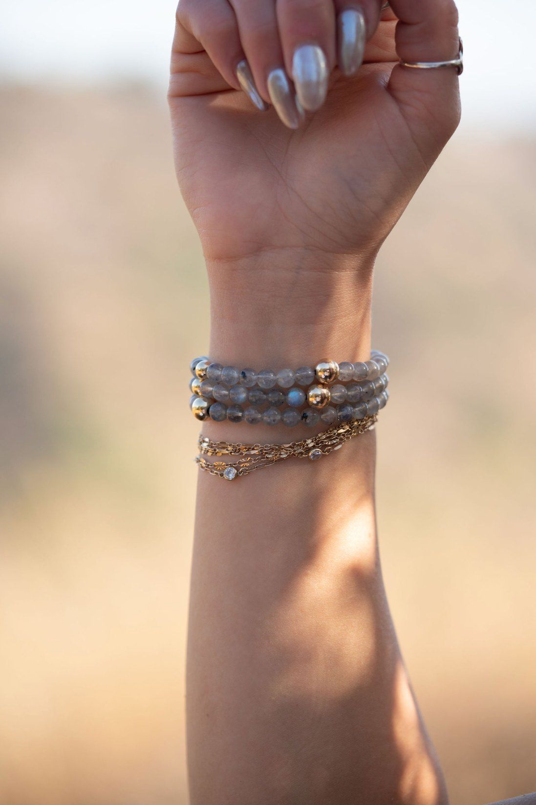 Labradorite and gold bracelets layered on a wrist