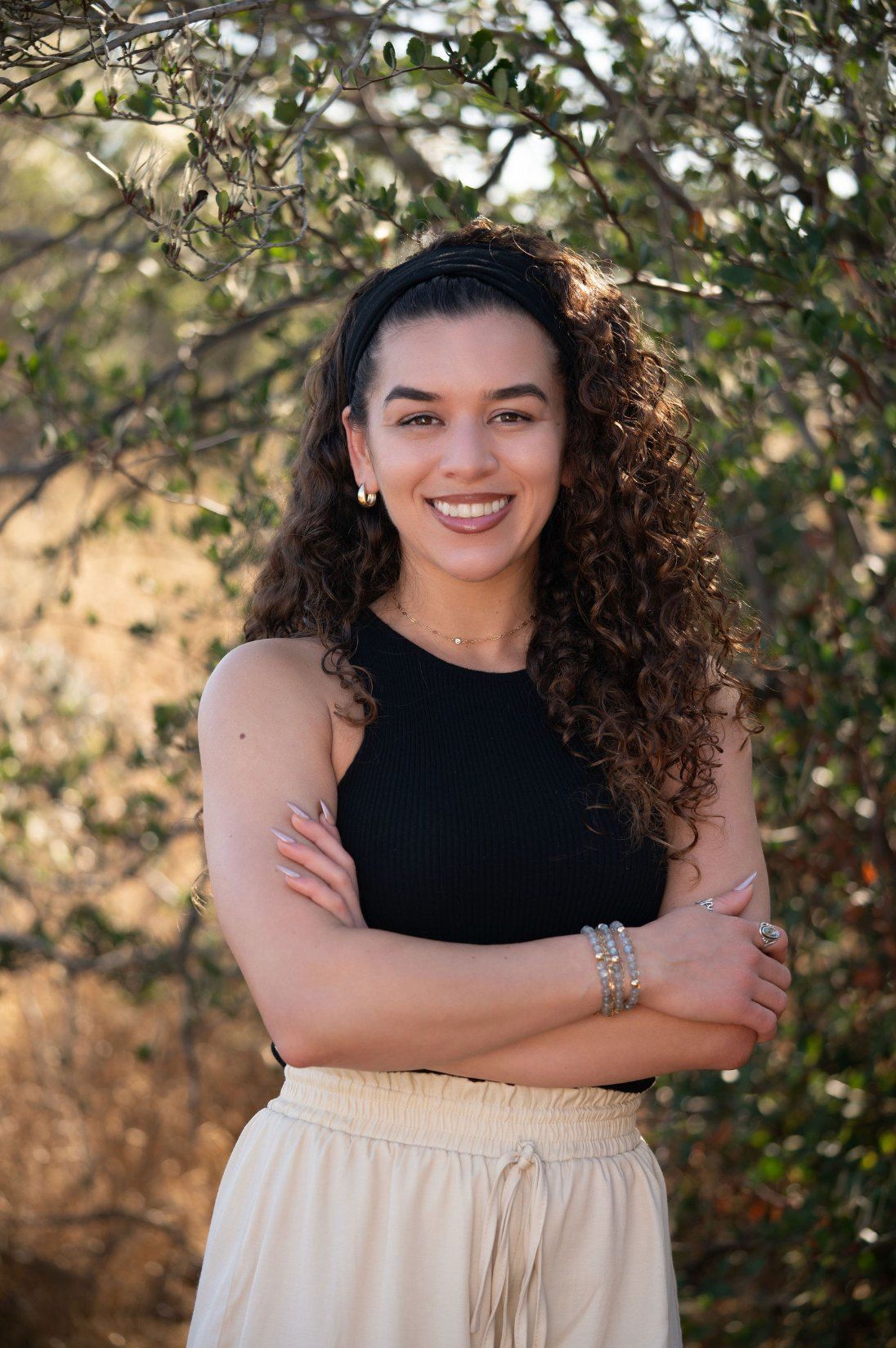 Char-Leen Christy-Rose smiling with her arms crossed, wearing a lapis stack